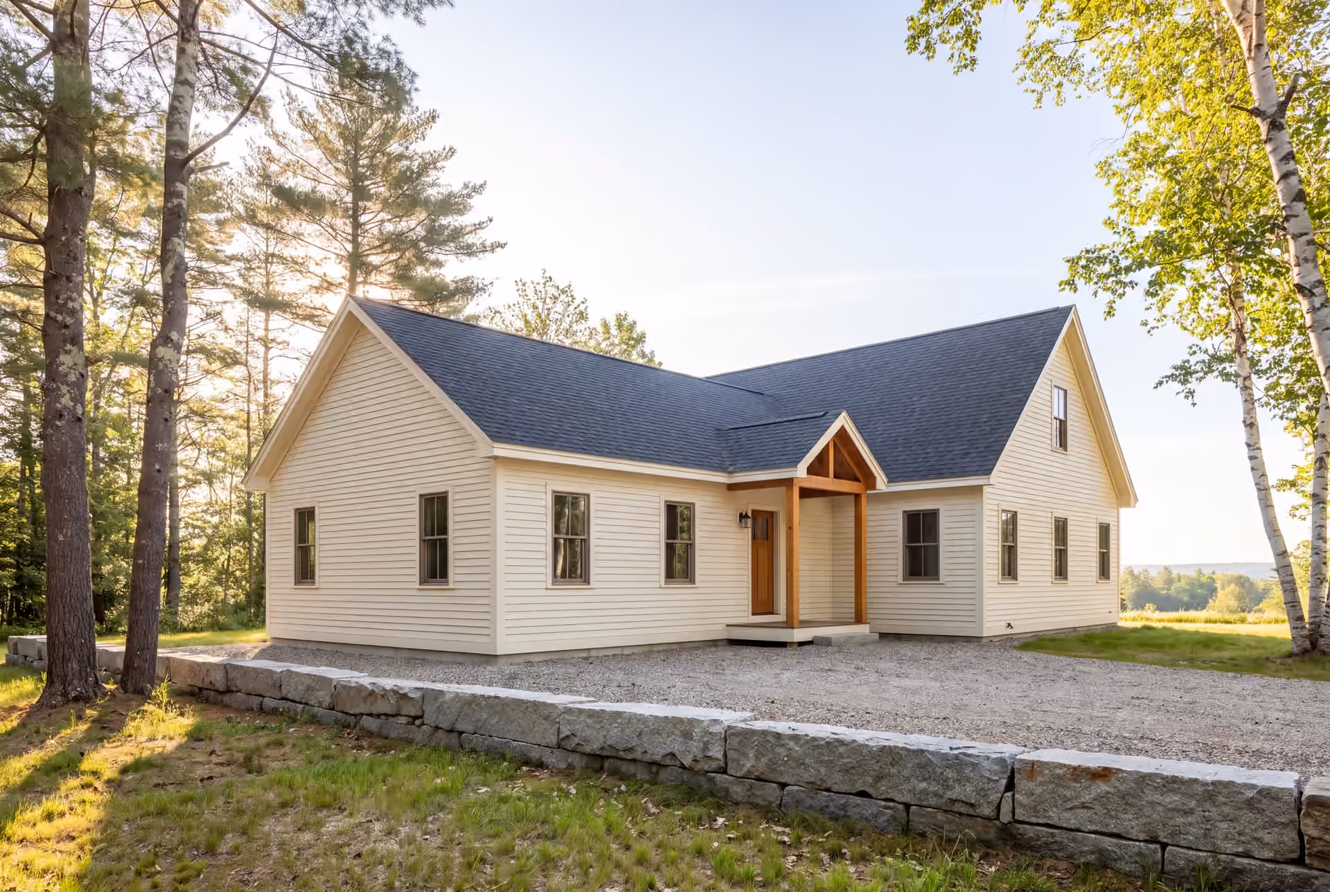 home addition builder in Biddeford, ME: illustrative scene, An exterior three-quarter view of a newly completed single-story house addition, featuring ivory clapboard siding and a dark gray gabled roof, connected to an existing home