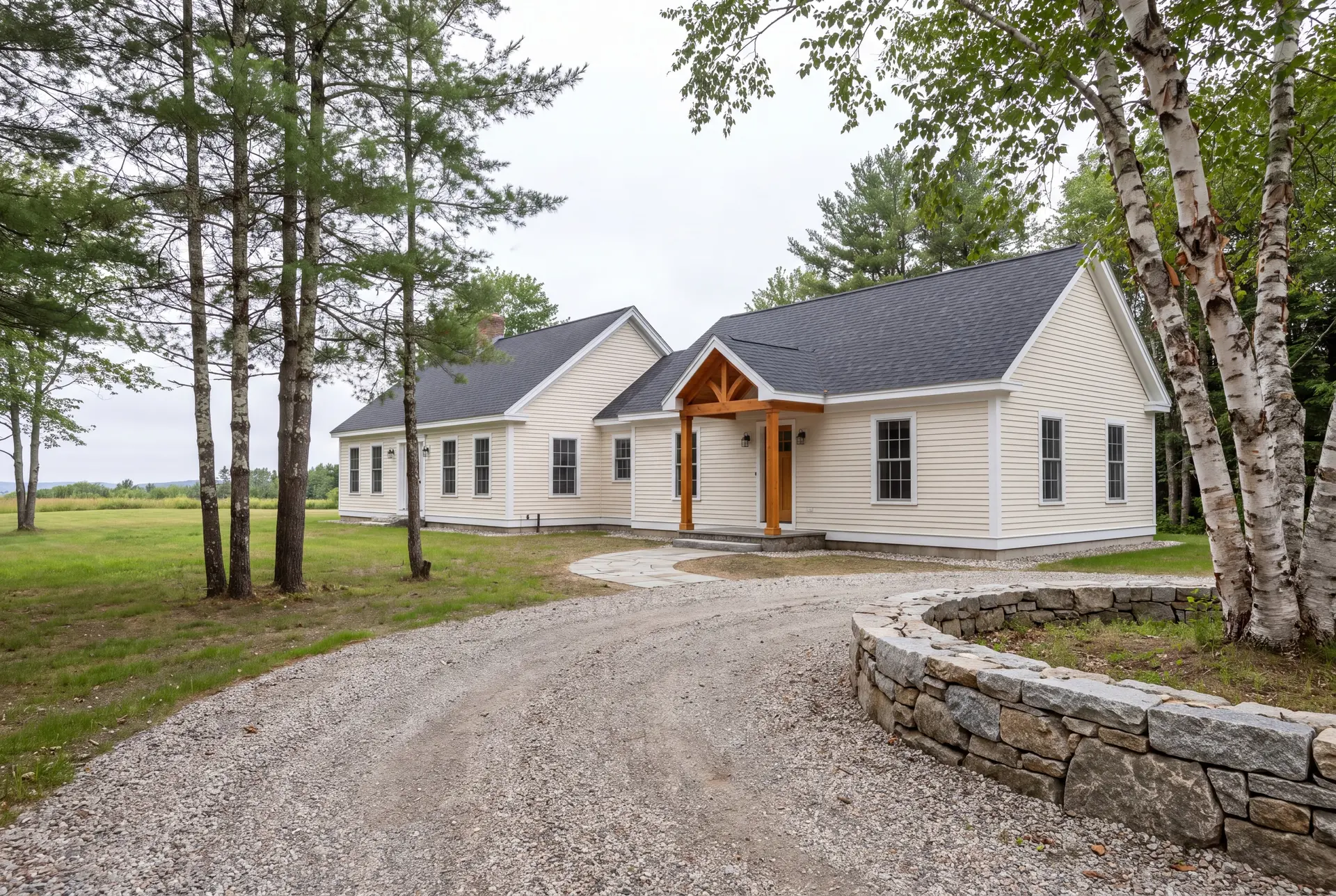 Illustration: A cream-colored single-story house with a new addition and a natural wood covered entry, seen from a three-quarter exterior view with a gravel driveway and trees