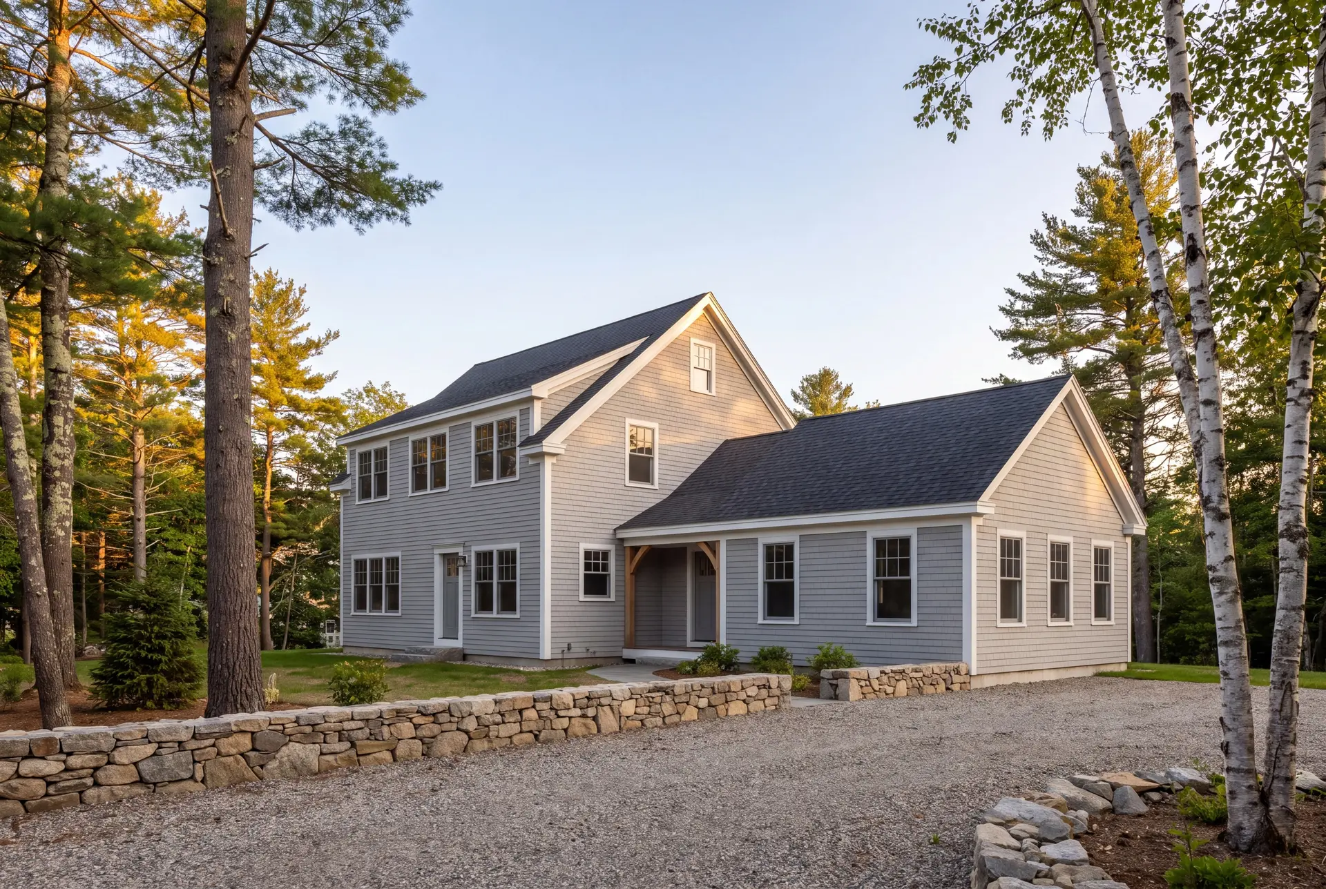 Illustration: A gray clapboard house with a new addition, surrounded by trees and a gravel driveway with a stone wall