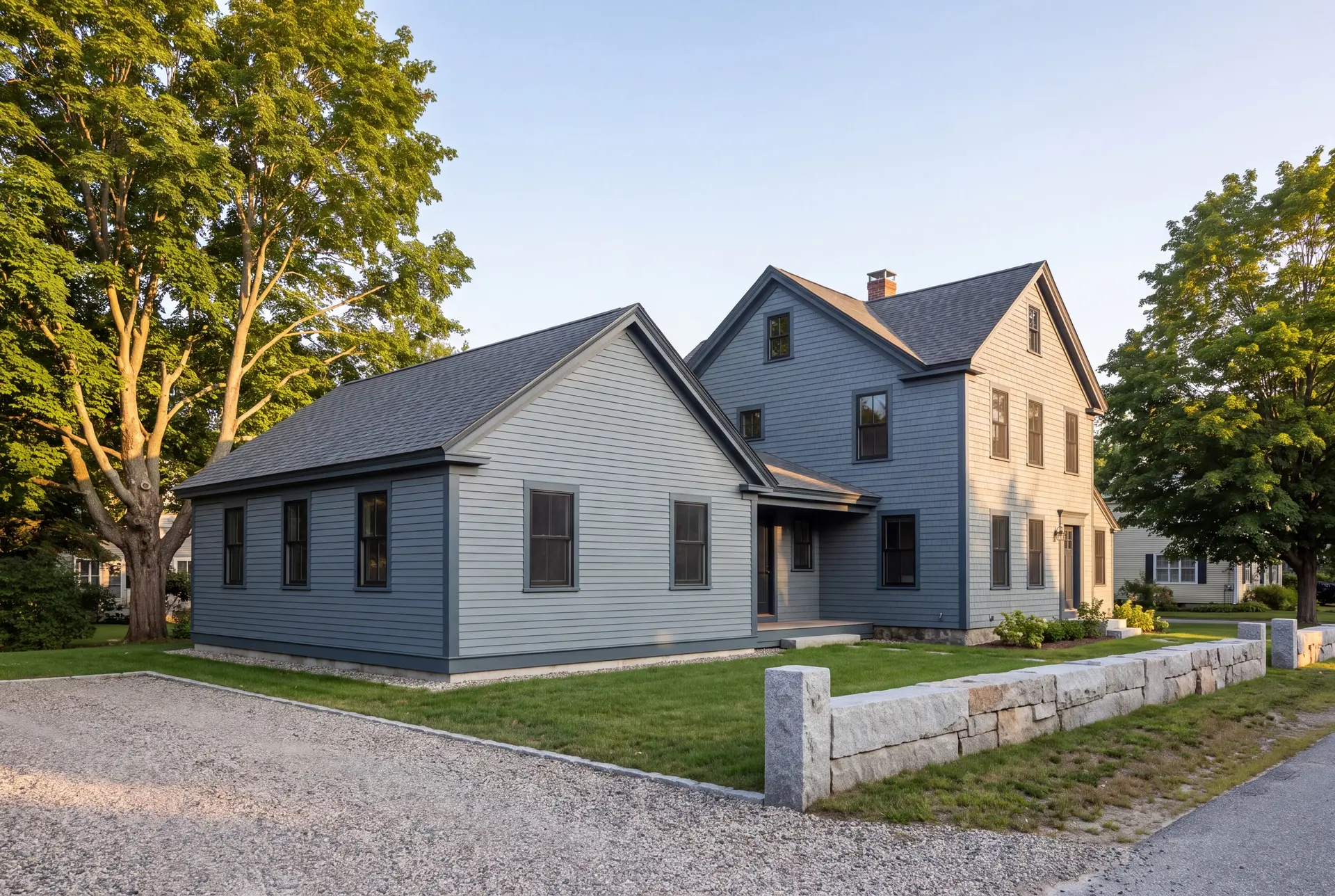 Illustration: A blue-gray house with a new single-story addition, a gravel driveway, and a stone wall under a clear sky