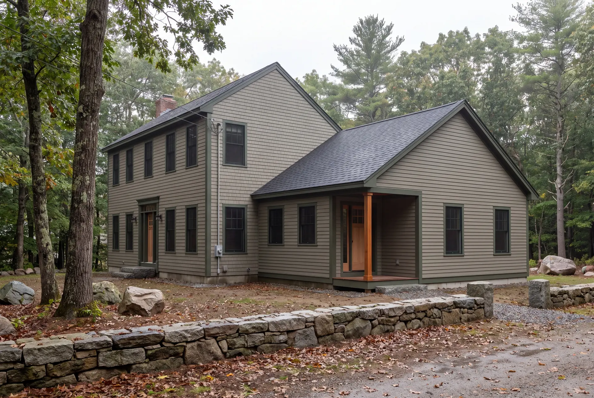 Illustration: An exterior view of a two-story house with a single-story addition, both in olive siding, surrounded by trees and a stone wall