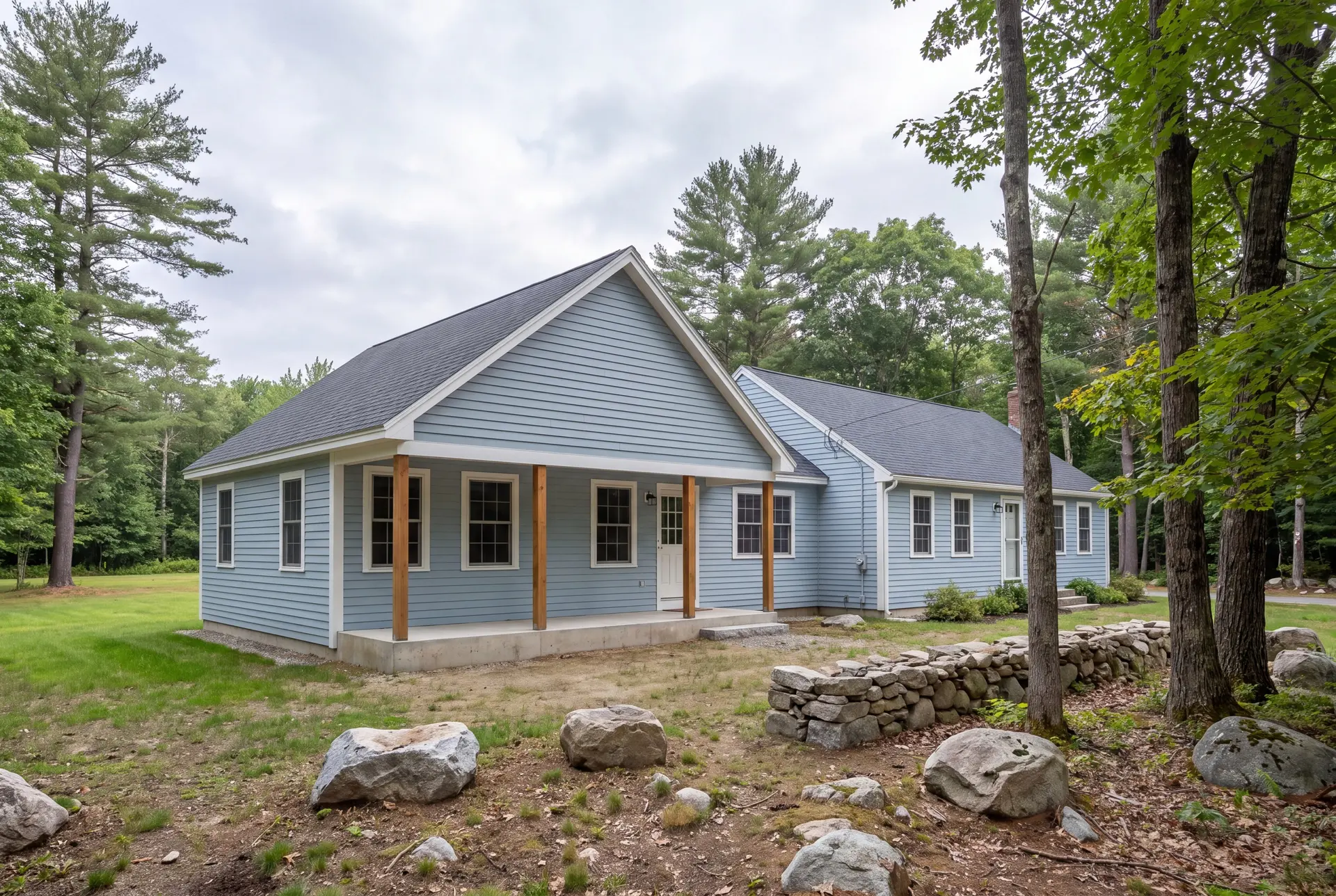 Illustration: A light blue clapboard house with a new addition and covered porch, surrounded by trees and rocks under a cloudy sky