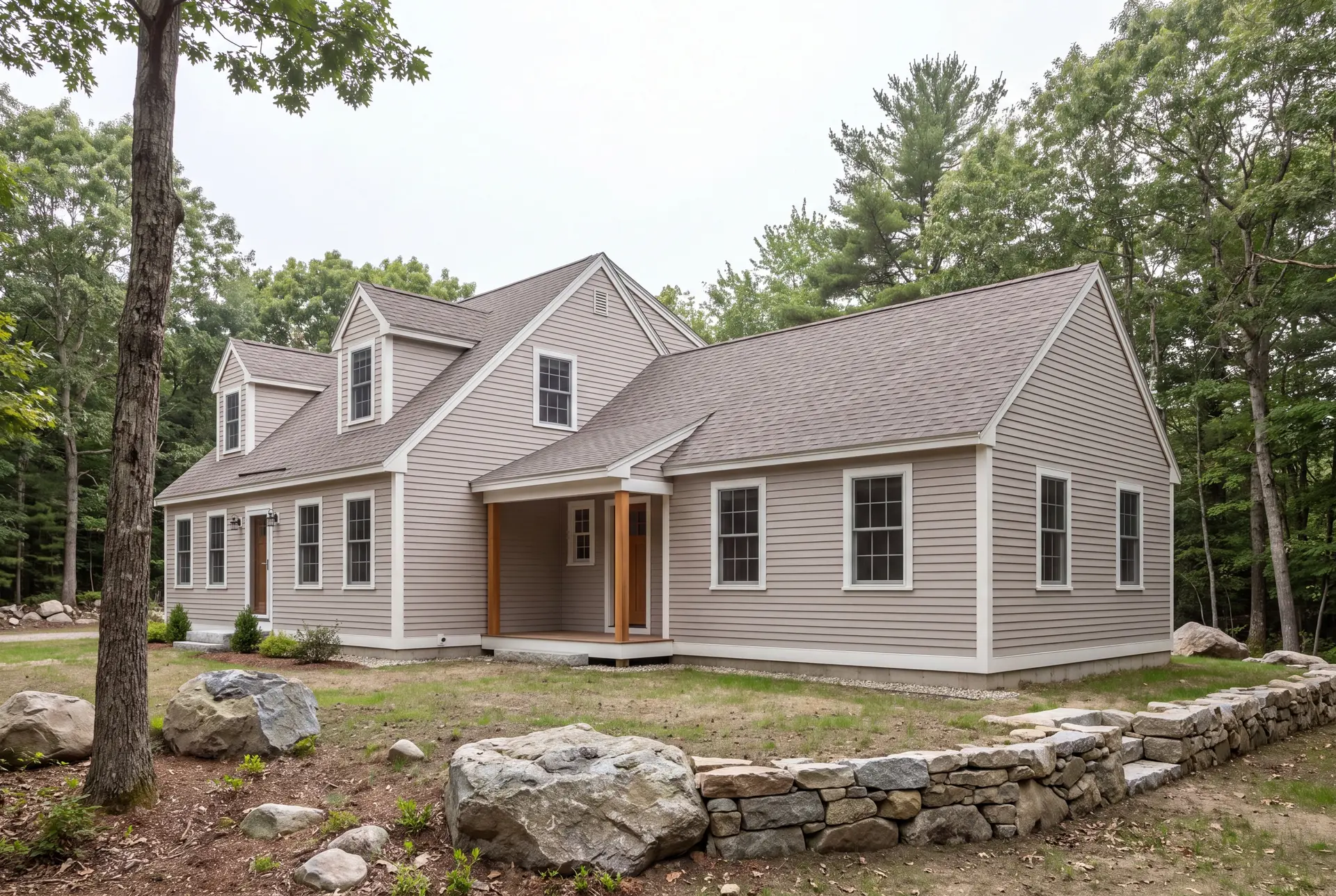 Illustration: A completed Cape-style house with a new single-story addition, both with mushroom-colored siding and a dark roof, surrounded by trees and rocks