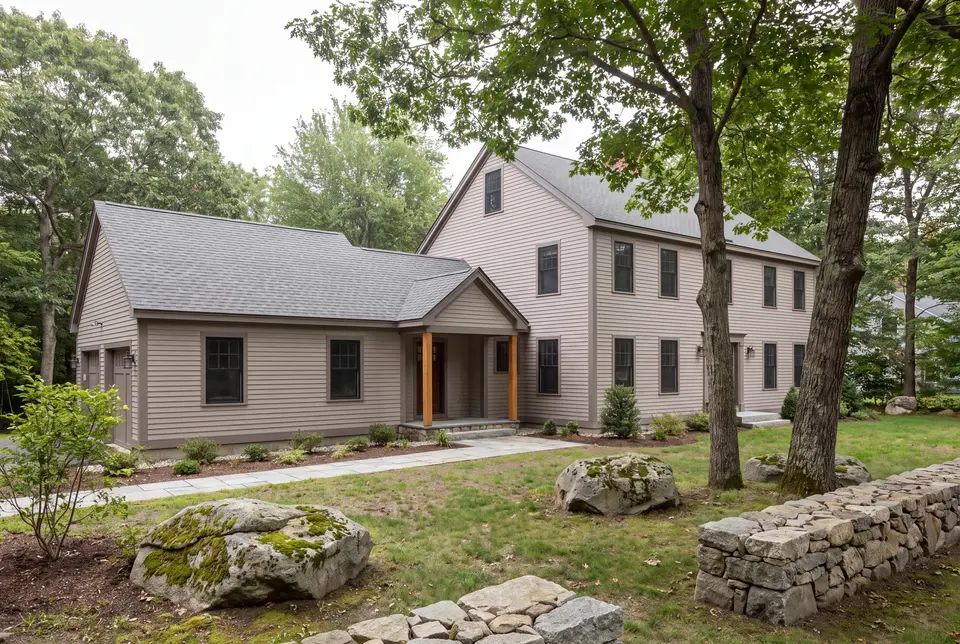 Illustration: A two-story Colonial house with a single-story addition, both in mushroom-colored clapboard siding, seen from a three-quarter exterior view with a stone path and trees in the foreground