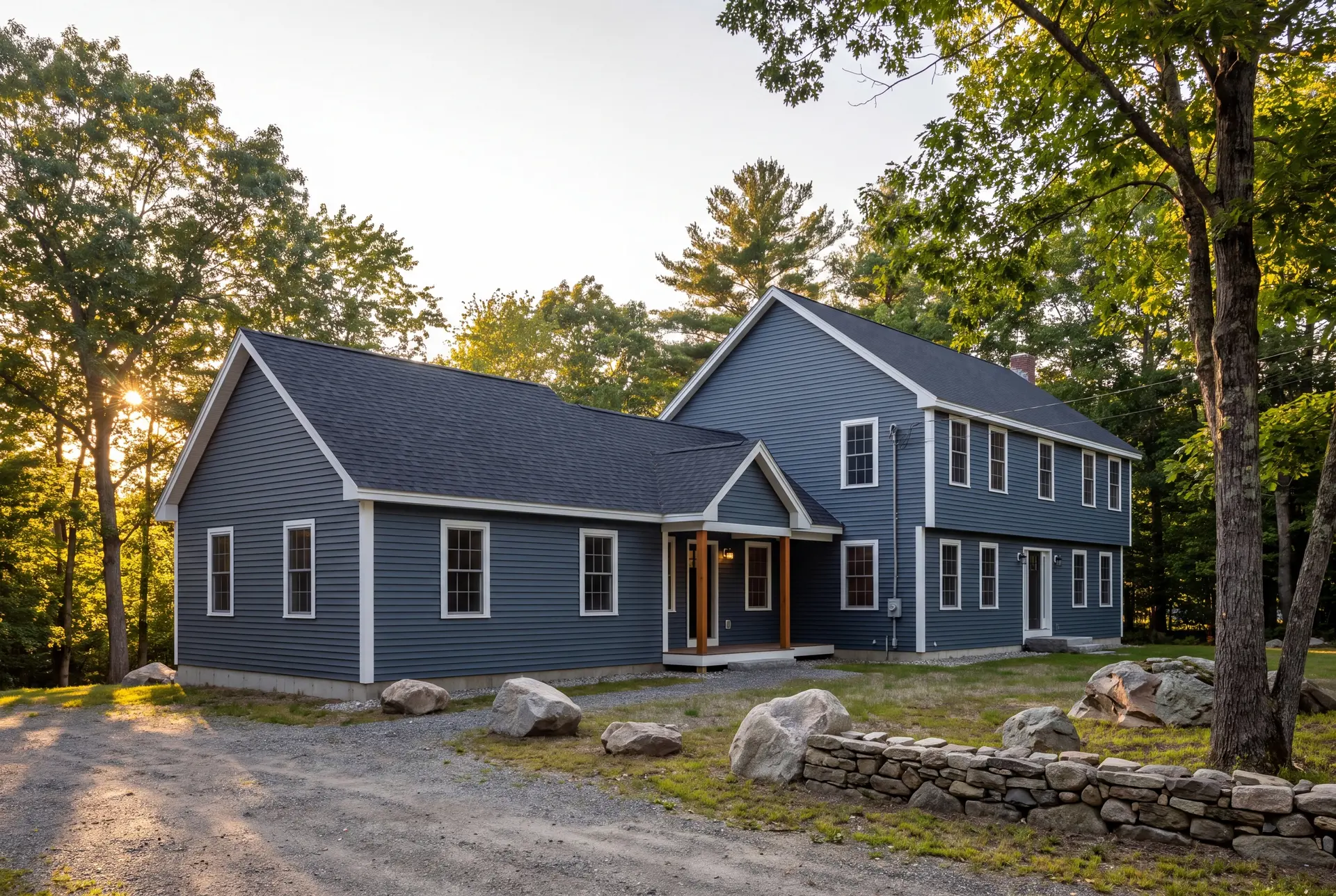 Illustration: A blue two-story house with a single-story addition, surrounded by trees and a gravel driveway, under a clear sky