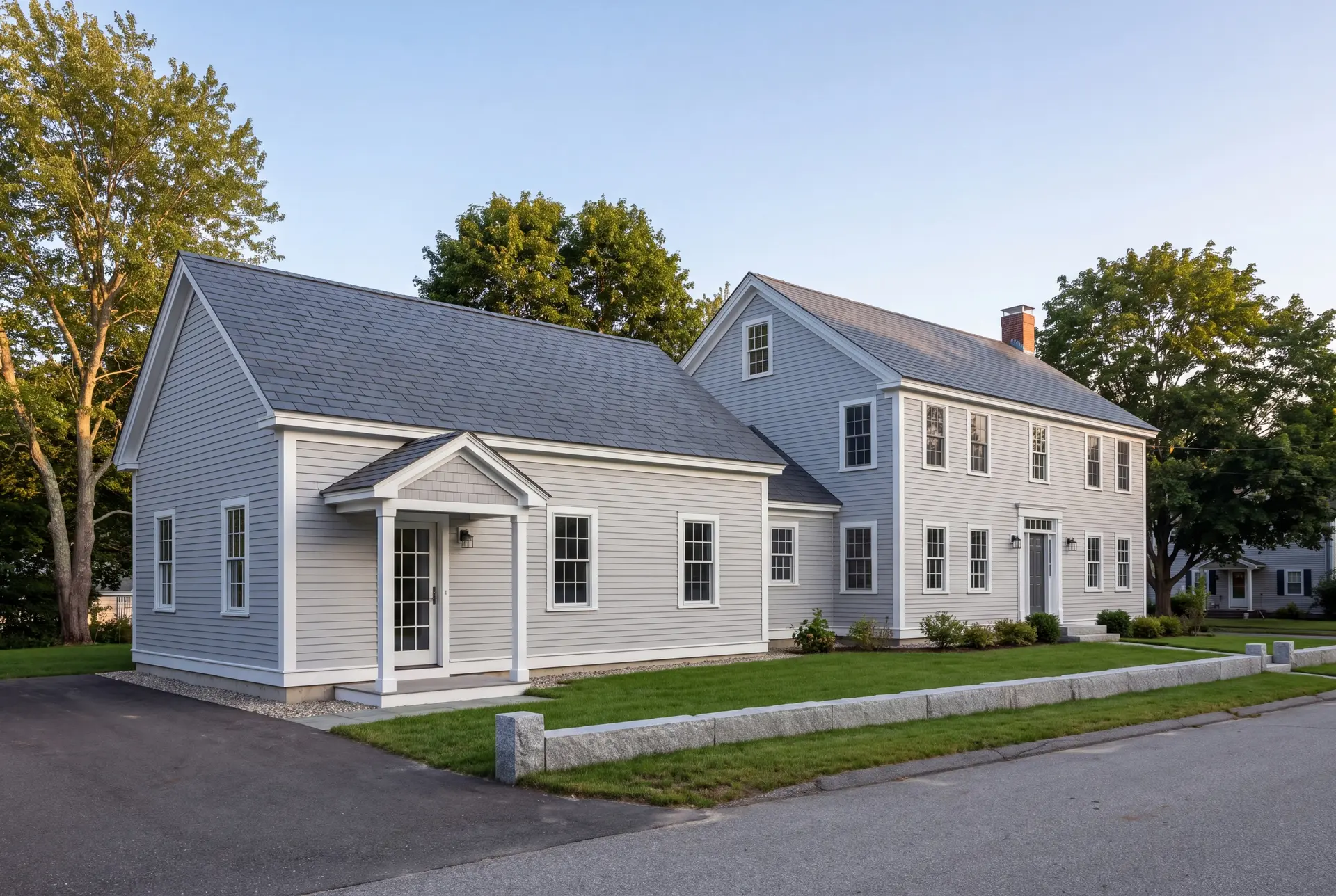 Illustration: A light gray Colonial house with a new single-story addition, featuring matching architectural details and a dark gray roof, viewed from a three-quarter exterior perspective