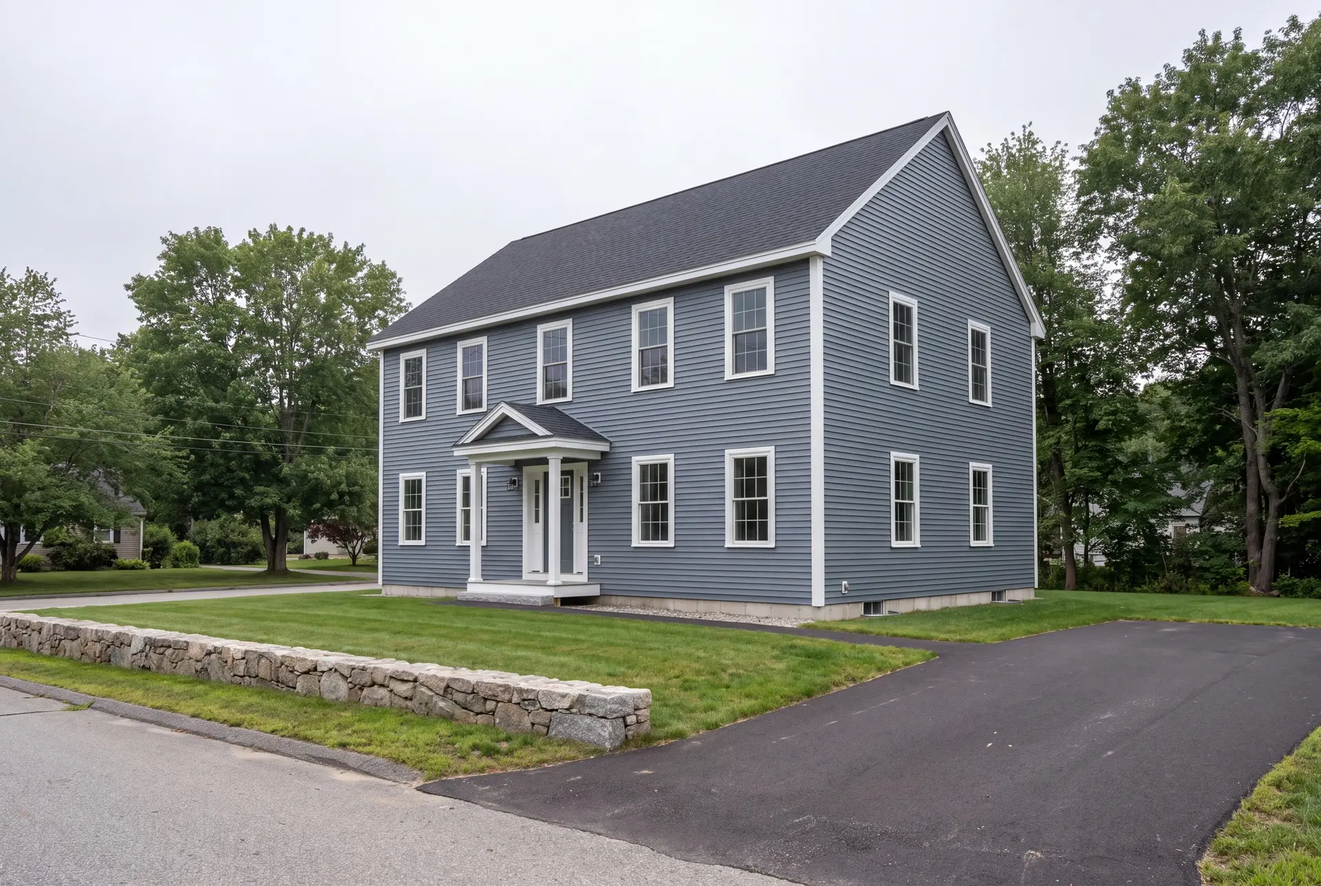 Illustration: A newly built two-story Colonial house with blue-gray siding and a dark roof, viewed from a three-quarter angle