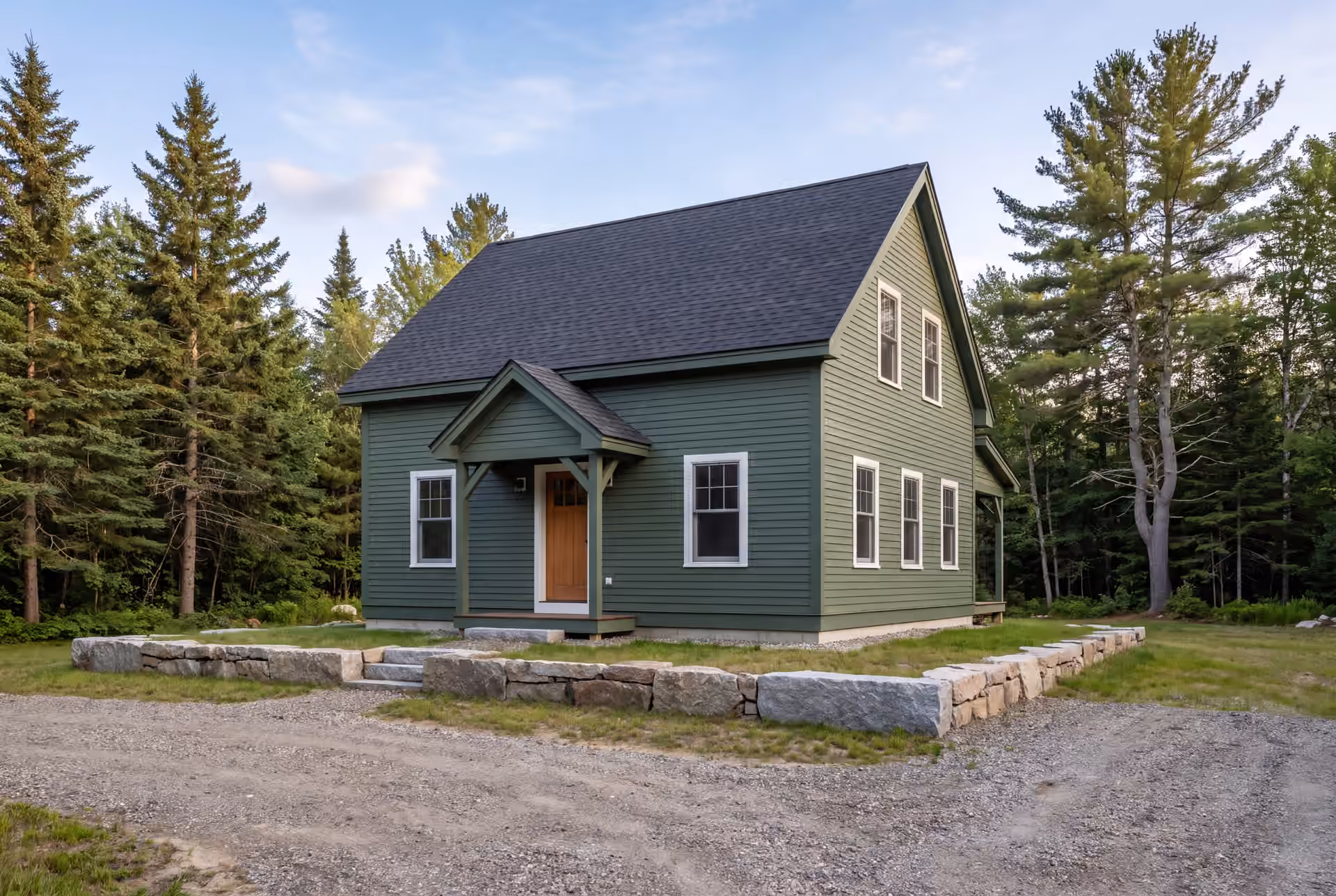 custom home builder in Cumberland, ME: illustrative scene, A green farmhouse with a dark roof and white windows, surrounded by trees and a gravel path