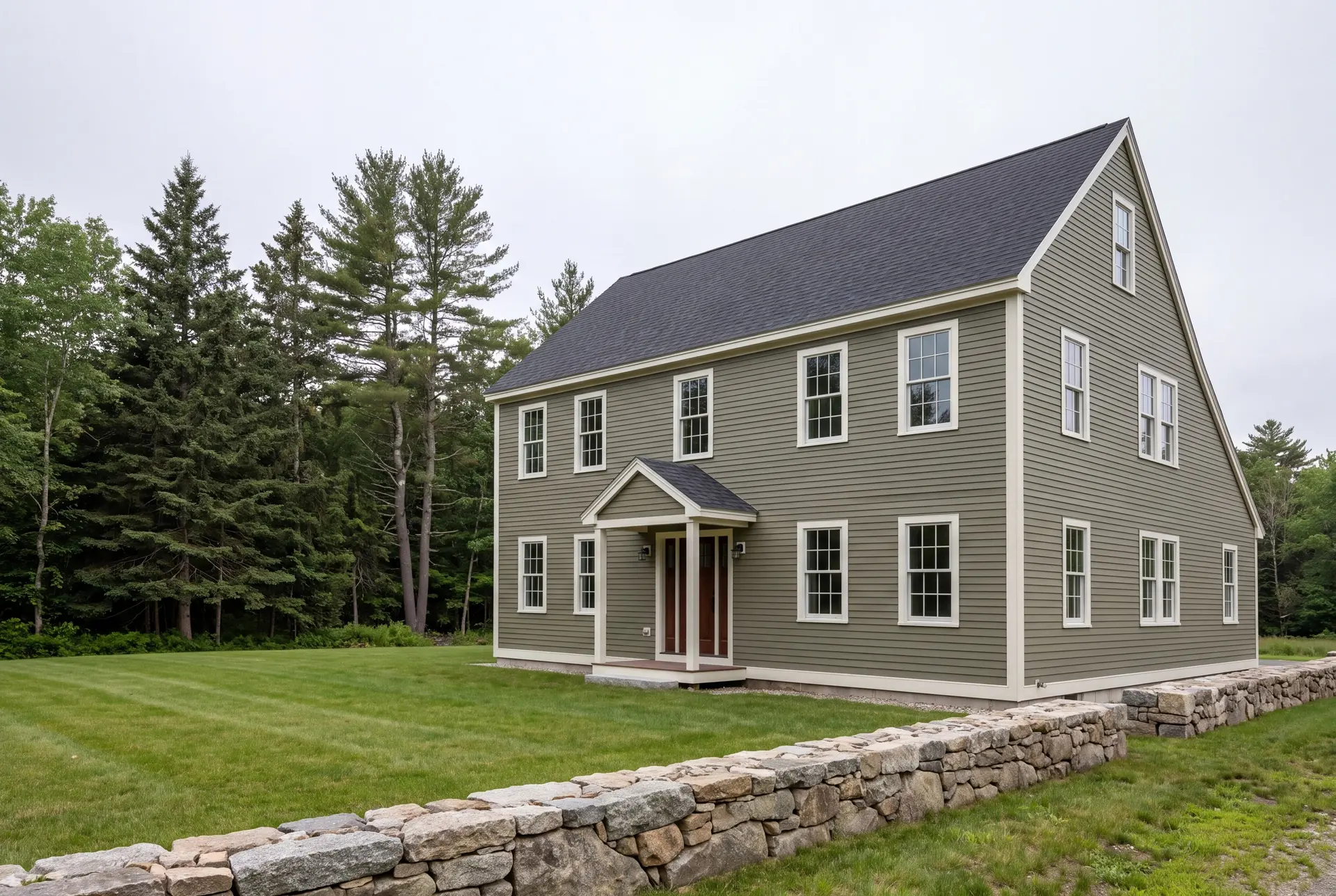Illustration: A newly built New England saltbox house with olive siding and a dark roof, surrounded by a green lawn and trees, with a stone wall in the foreground