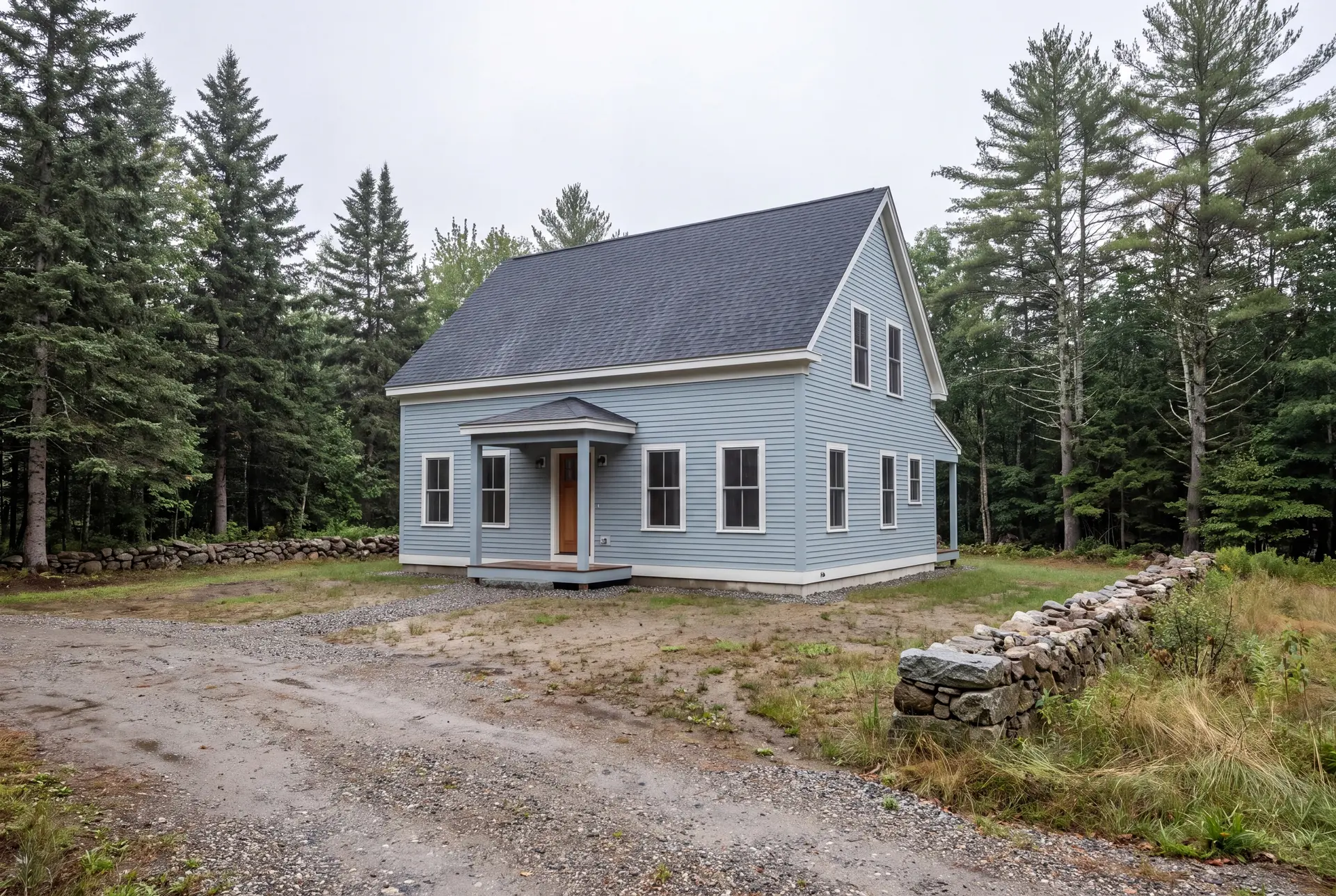 Illustration: A light blue farmhouse with a dark roof and white trim, surrounded by pine trees and a gravel driveway