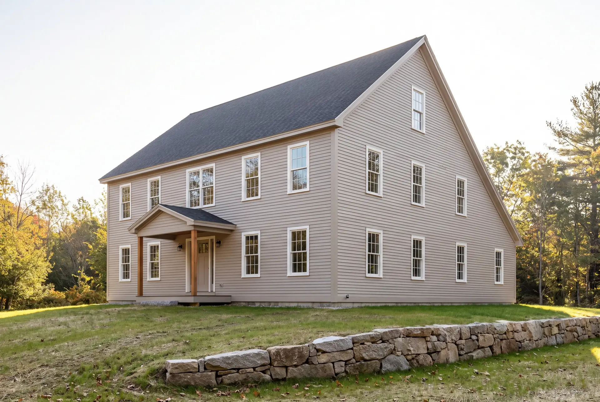 Illustration: A newly built traditional New England saltbox house with mushroom siding, a dark roof, and white-trimmed windows, seen from a three-quarter angle on a sunny day