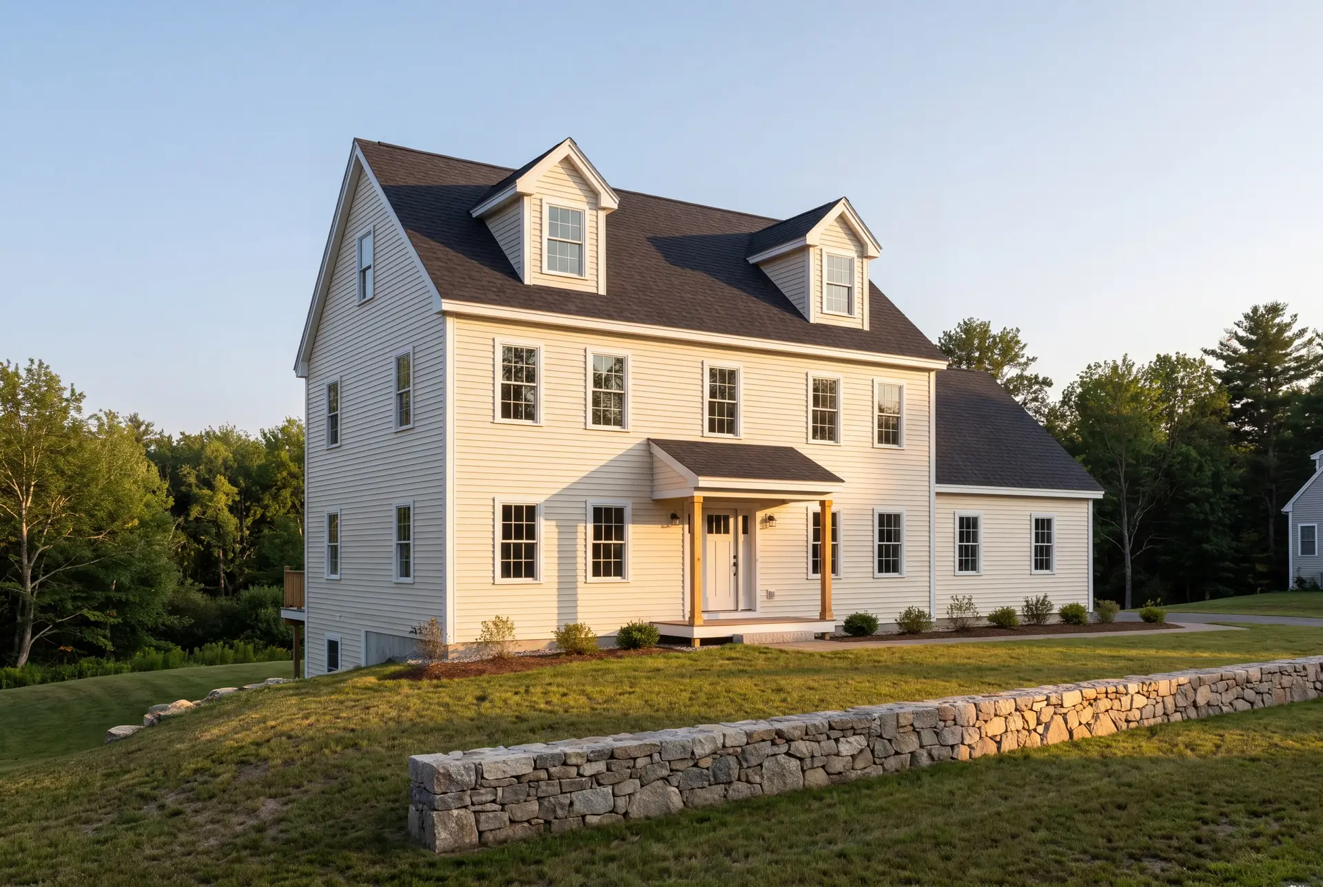 Illustration: A newly built Cape-style house with ivory siding, a dark roof, and a covered porch, set on a green lawn with a stone wall