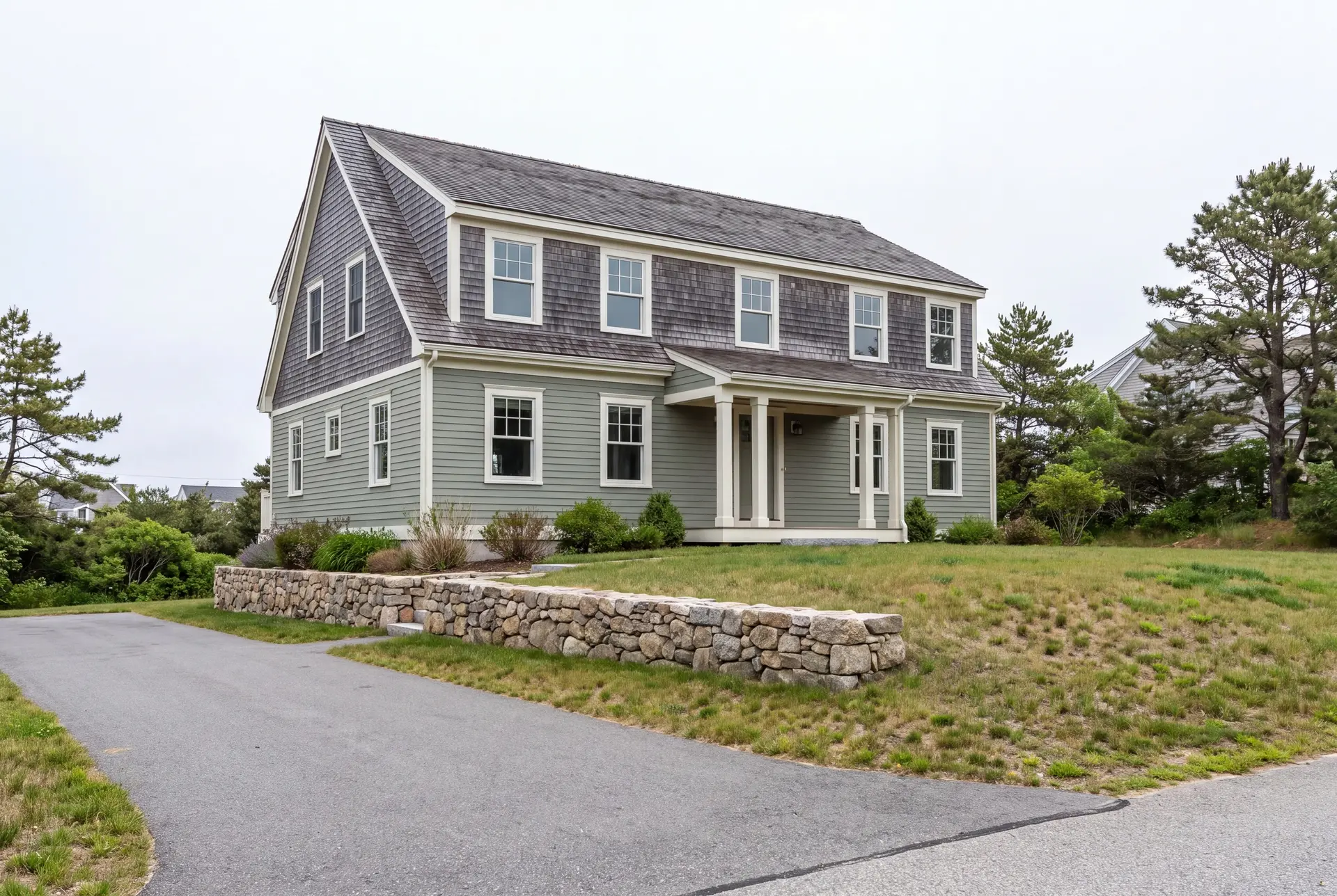 Illustration: A two-story shingle-style house with sage green clapboard and gray shingle siding, a charcoal roof, and white-trimmed windows, viewed from a three-quarter angle