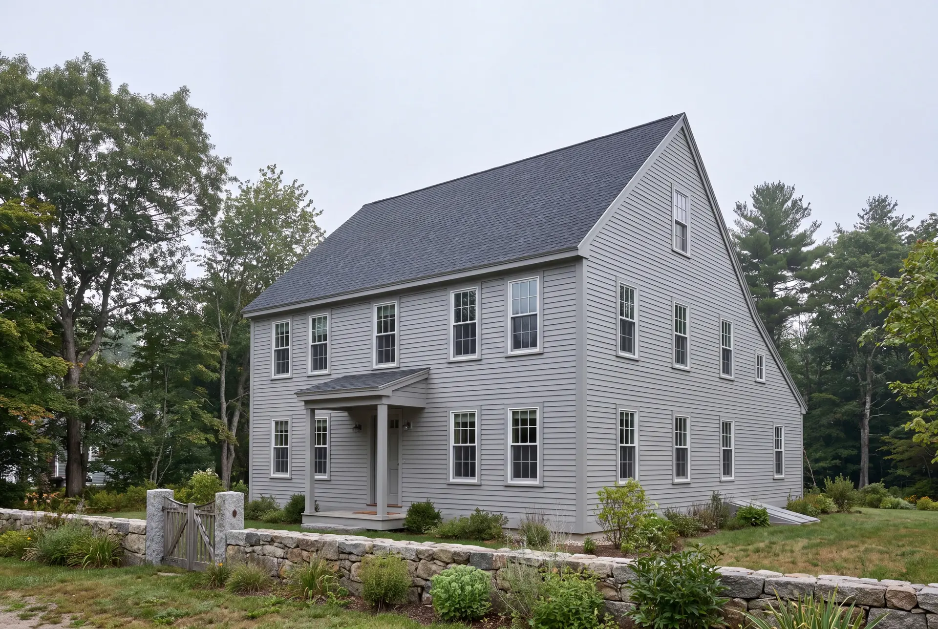 Illustration: A gray saltbox house with a dark roof and white windows, seen from a three-quarter view, with a stone wall and gate in the foreground
