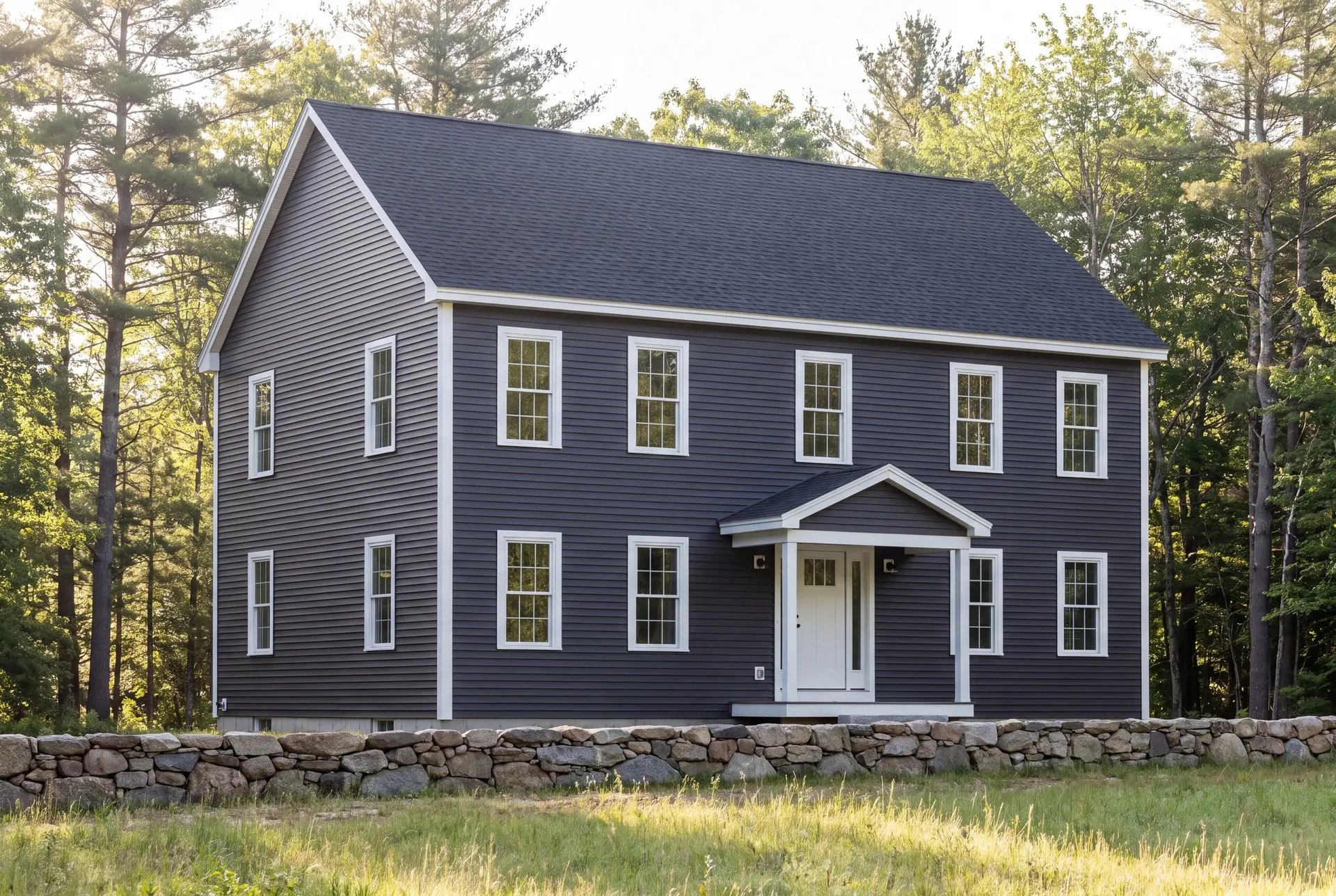 Illustration: A newly built two-story Colonial house with dark gray siding, a dark gray roof, and white-trimmed windows, set against a backdrop of trees and a stone wall
