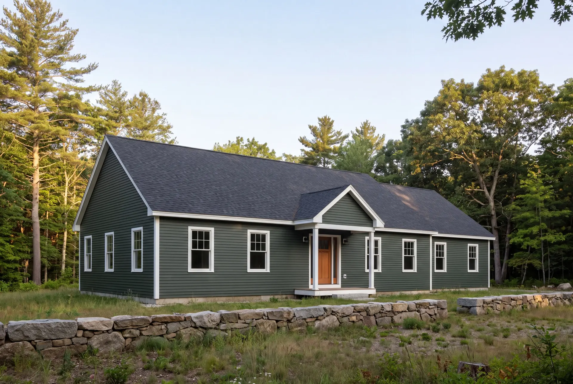 Illustration: A newly built green ranch house with a dark roof and white trim, surrounded by trees and a stone wall