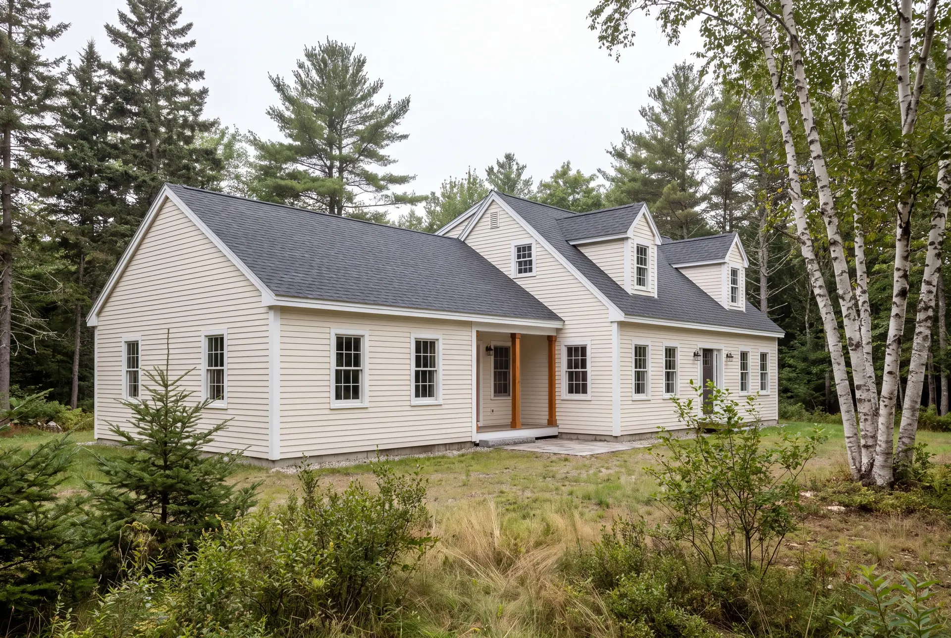 Illustration: A cream-colored house with a dark gray roof and an attached single-story addition, set in a natural, wooded environment