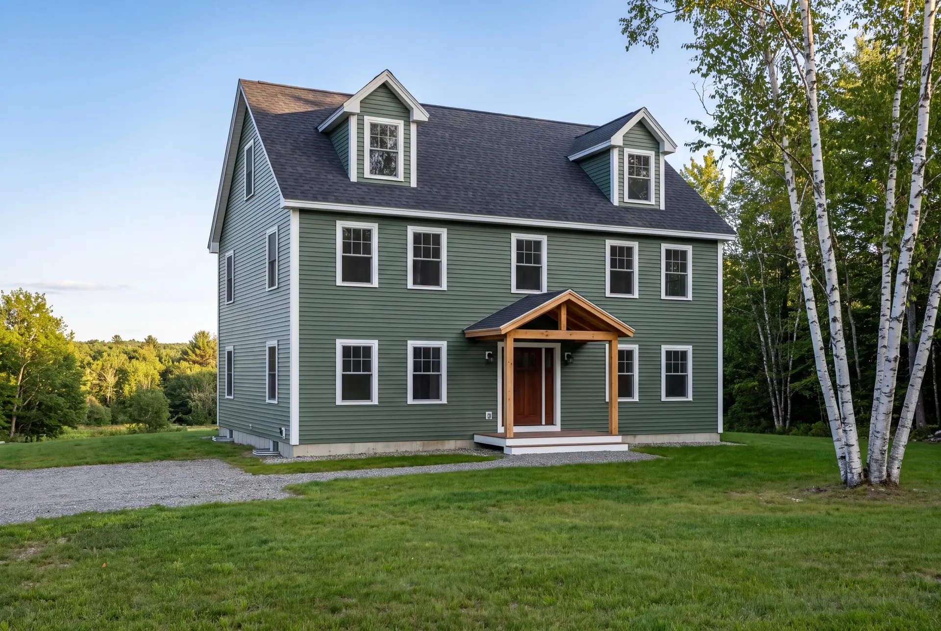 Illustration: A newly built green Cape house with a dark roof and a wooden porch, surrounded by a green lawn and trees under a clear sky