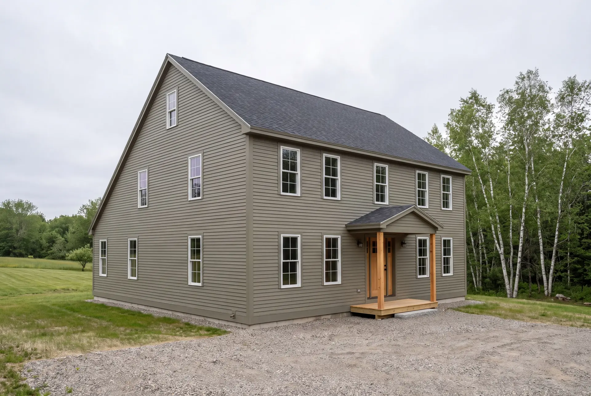 Illustration: A newly built two-story house with olive green siding, a dark gray roof, and white windows, featuring a wooden porch with natural timber posts, set against a backdrop of trees and a grassy field