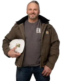 Joe Hausler wearing a brown jacket and holding a white Legacy Construction hard hat