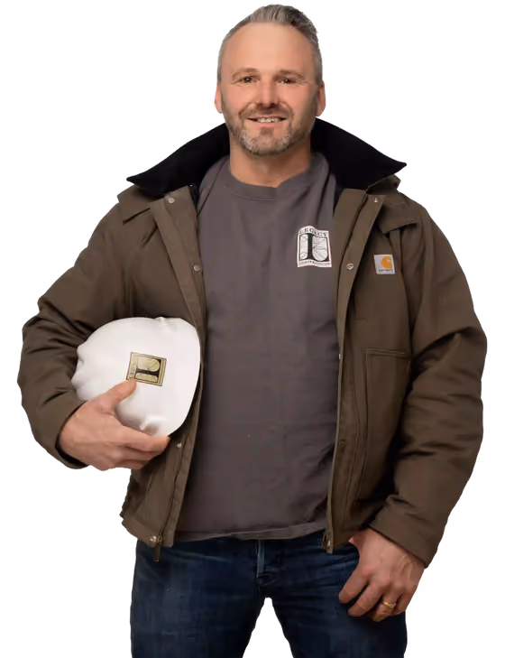 Joe Hausler wearing a brown jacket and holding a white Legacy Construction hard hat