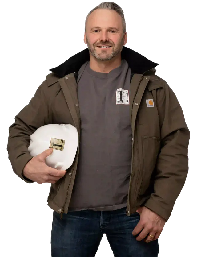 Joe Hausler wearing a brown jacket and holding a white Legacy Construction hard hat